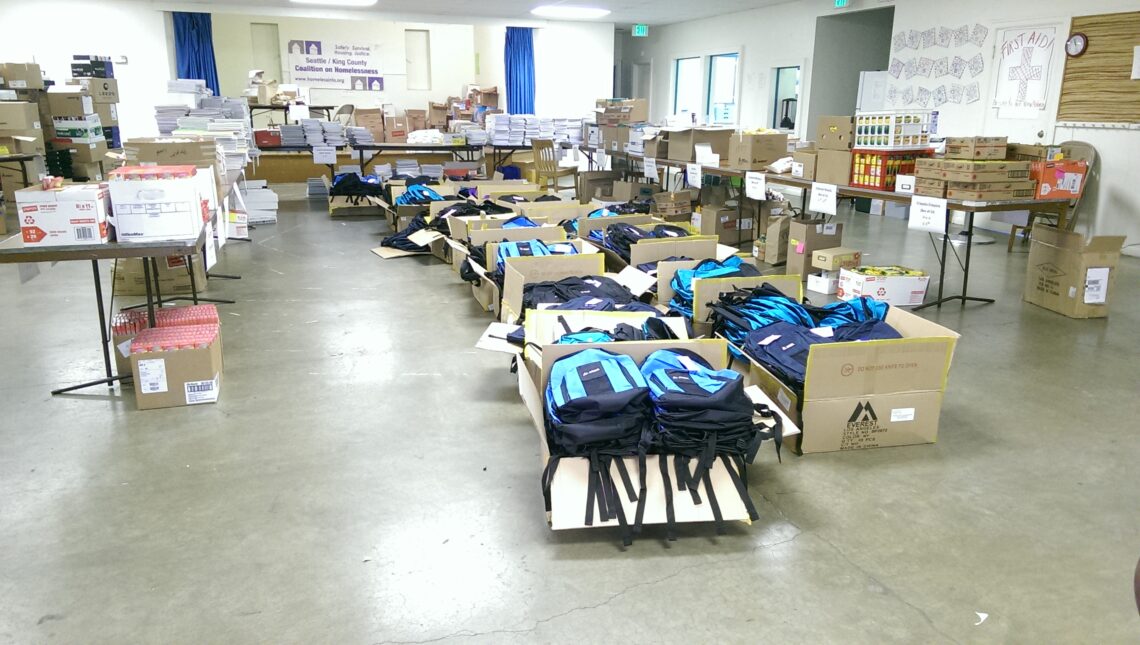 A sparsely decorated room, with tables of backpacks and school supplies intended for the Seattle/King County Coalition on Homelessness’ Project cool.